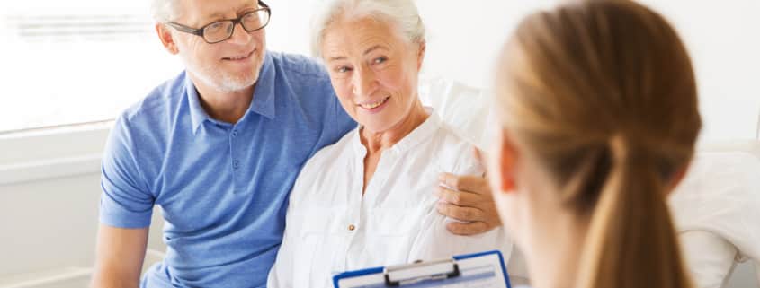 senior woman and doctor with clipboard at hospital